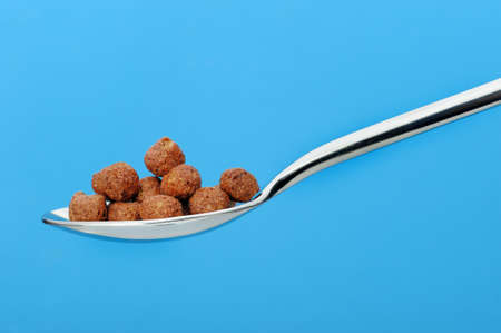 Chocolate cornflakes. A dry breakfast in a spoon. On a blue backgroundの写真素材