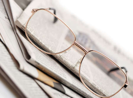 Eyeglasses lie on a pile of newspapers. A photo close up. Selective focusの写真素材