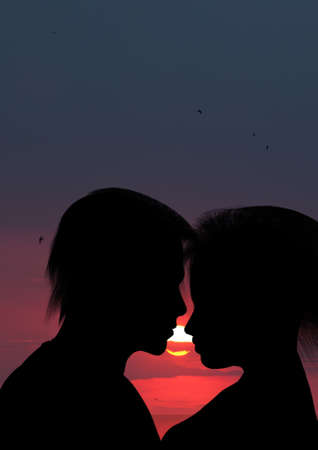 Silhouette kissing a loving couple. Against sunsetの写真素材