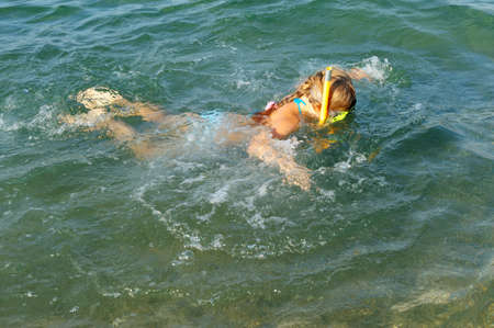 The girl floats under water. In a mask, flippers and with a snorkelの写真素材