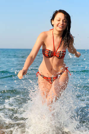 The joyful woman runs on sea waterの写真素材