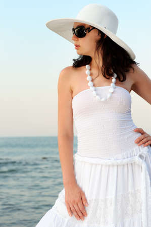 The woman on seacoast. In sun glasses, a sundress, a hat.の写真素材