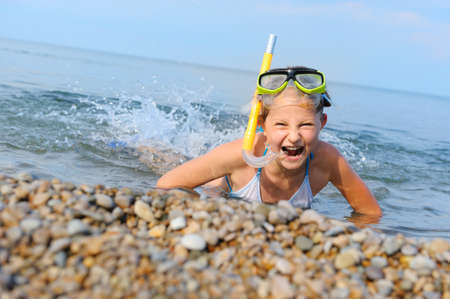 The girl on seacoast flounders about in water. In a mask, flippers and with a snorkelの写真素材