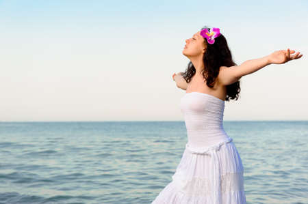 The woman in a white sundress on seacoast with open hands. A picturesque landscapeの写真素材