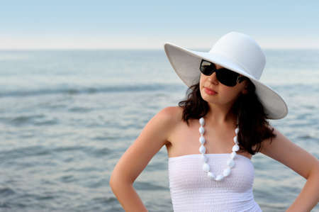 The woman on seacoast. In sun glasses, a sundress, a hat.の写真素材