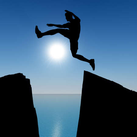 Silhouette of the jumping man from a rock. A shining sun with beamsの写真素材