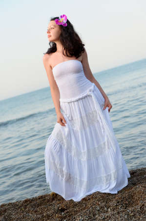 The woman in a white sundress on seacoast. A picturesque landscapeの写真素材