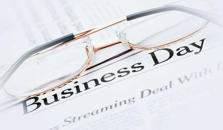 Eyeglasses lie on the newspaper with title Business day.Blue toned. A photo close up. Selective focusのeditorial素材
