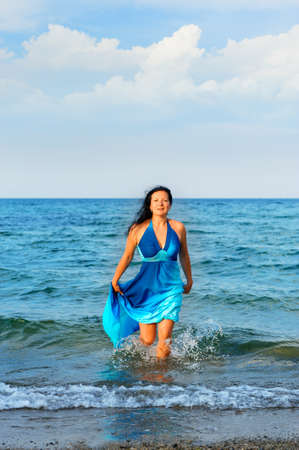 The attractive woman exit the sea. A dark blue dressの写真素材