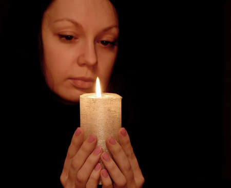 The woman with burning candle. Selective focus on a candleの写真素材