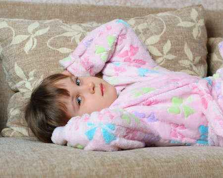 The little girl lies on a sofa. Home roomの写真素材