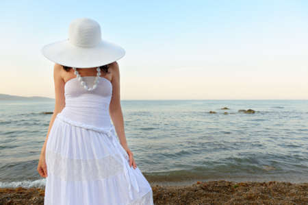 The woman on seacoast. In sun glasses, a sundress, a hat.の写真素材