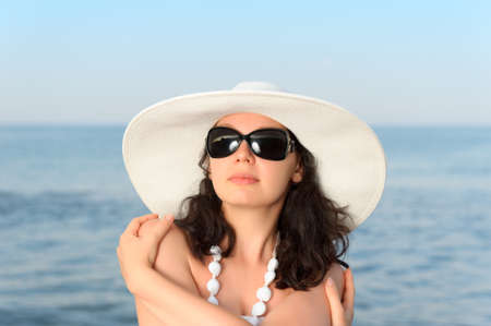 The woman on seacoast. In sun glasses, a sundress, a hat.の写真素材