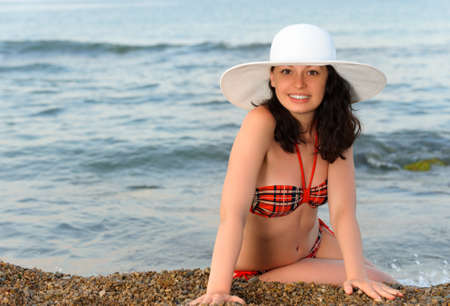 The woman sits on seacoast. In a white hat.の写真素材