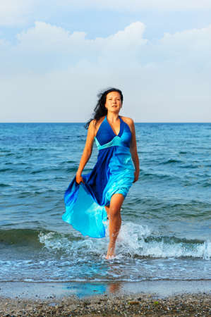 The attractive woman exit the sea. A dark blue dressの写真素材