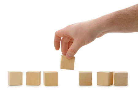 The hand establishes a wooden cube in row. It is isolated on a white backgroundの写真素材