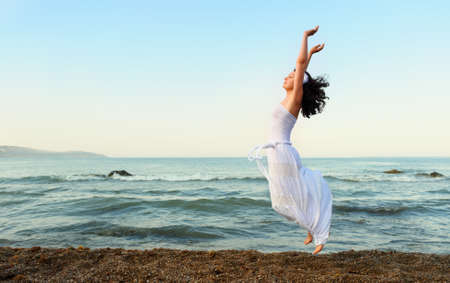 The young woman jumps on seacoast. A picturesque landscapeの写真素材