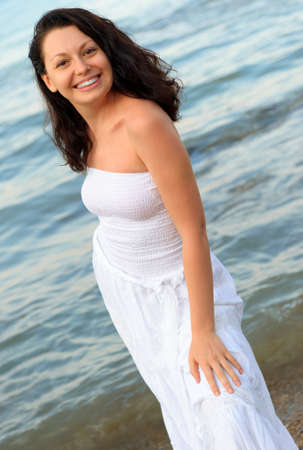 The woman in a white sundress on seacoast. A picturesque landscapeの写真素材