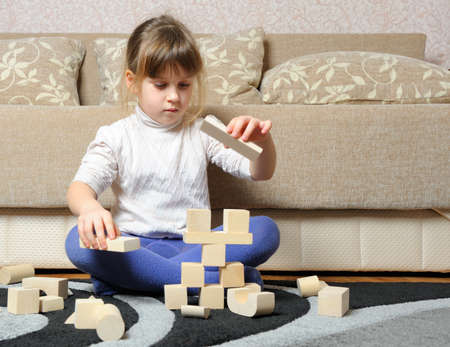 The little girl plays wooden toy cubes. A house roomの写真素材