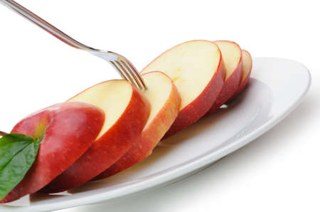 Apple sliced sections. Fruit on a plate with fork isolated on white backgroundの写真素材