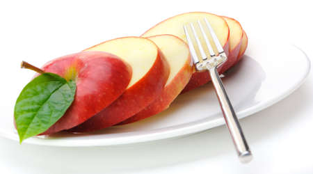 Apple sliced sections. Fruit on a plate with fork isolated on white backgroundの写真素材