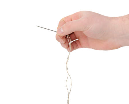 Needle and thread in hand closeup. Isolated on white backgroundの写真素材