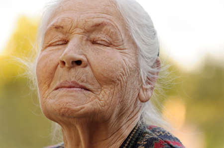 The elderly woman with closed eyes. A photo outdoorsの写真素材