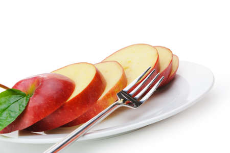 Apple sliced sections. Fruit on a plate with fork isolated on white backgroundの写真素材