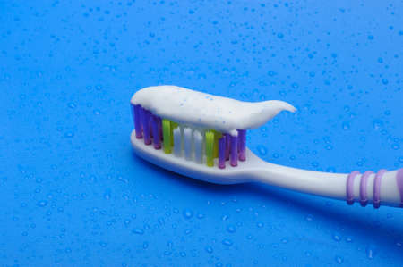 Toothbrush on a blue background with the toothpaste and drops of water .の写真素材