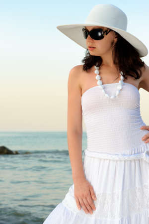 The woman on seacoast. In sun glasses, a sundress, a hat.の写真素材