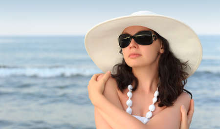 The woman on seacoast. In sun glasses, a sundress, a hat.の写真素材
