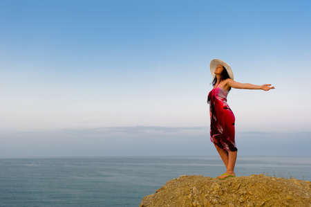 The woman on a mountain with open hands, against the blue skyの写真素材