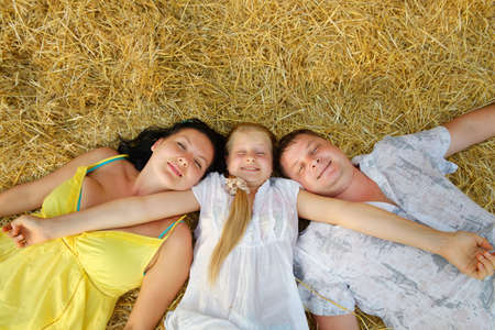 A young family, father, mother and daughter. Lie on hayの写真素材