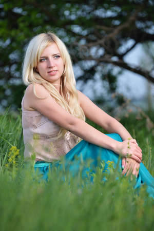 Portrait of a pretty woman sitting in the grass. Shooting outdoorsの写真素材