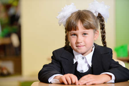 schoolchild with white bows and black suite with white bows. Sitting at a Deskの写真素材