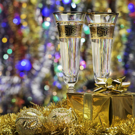 Glasses with champagne and a gift. Christmas objects, the bright lights and colorsの写真素材