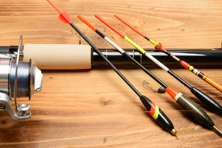 Objects for fishing. The rod with reel, a float, fishing line and hook on a wooden surfaceの写真素材