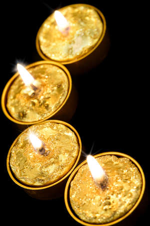 Golden burning candles on a black background.の写真素材