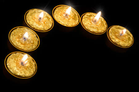 Golden burning candles on a black background.の写真素材