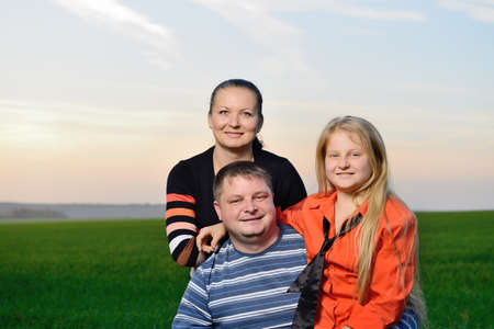 Happy young family. The green field and picturesque sky