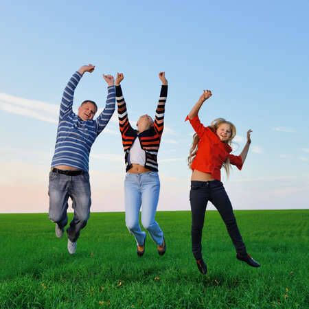 Happy young family jump for joy . The green field and picturesque skyの写真素材