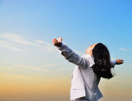 A woman in a business suit with their hands raised . On the background of the picturesque skyの写真素材