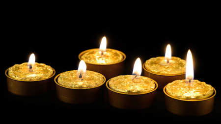 Golden burning candles on a black background.の写真素材