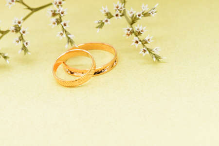 Gold wedding rings and branch flowers. Holiday postcard yellow textured old paperの写真素材