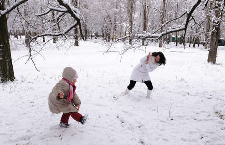 Mum and the daughter play snowballs on the natureの写真素材