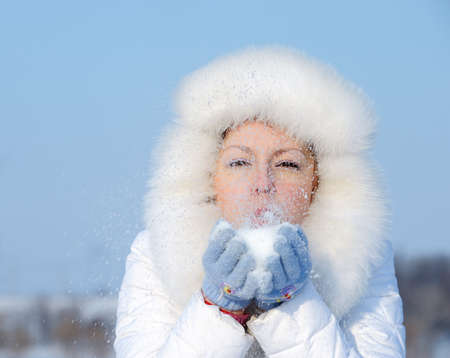 Girl blows off snowflakes from the hand. Blue skyの写真素材