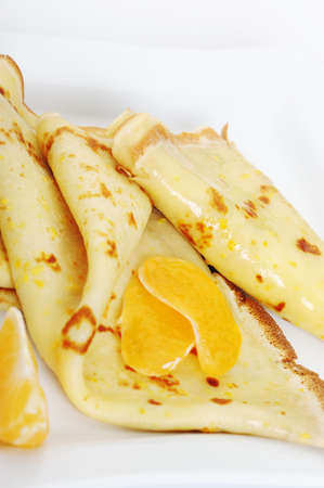 Crepe on a plate with mandarin. It is isolated on a white background. A detailed photo fried thin pancake.の写真素材