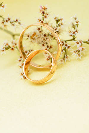 Gold wedding rings and branch flowers. Holiday postcard yellow textured old paperの写真素材