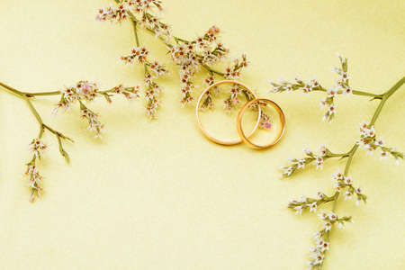 Gold wedding rings and branch flowers. Holiday postcard yellow textured old paperの写真素材