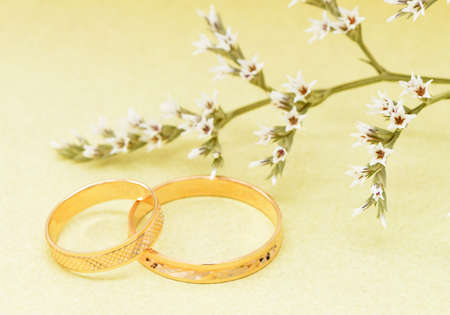 Gold wedding rings and branch flowers. Holiday postcard yellow textured old paperの写真素材